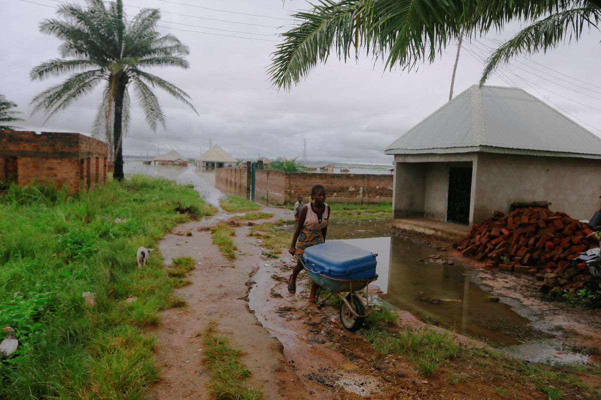 A woman pushes a wheelbarrow with a box as flood water displaces residents living close to River Beune bank in Makurdi Nigeria, 1 October 2022. Photo: Afolabi Sotunde /  REUTERS