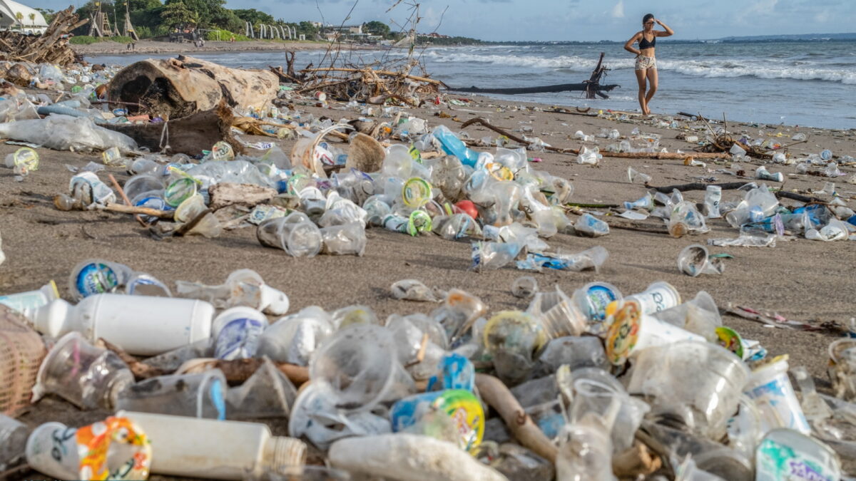 Plastic Waste in Canggu Beach, Bali. A tourist walks along a beach covered in piles of debris and plastic waste in Canggu, Bali, Indonesia, 12 December 2021. Photo: Made Nagi / Greenpeace