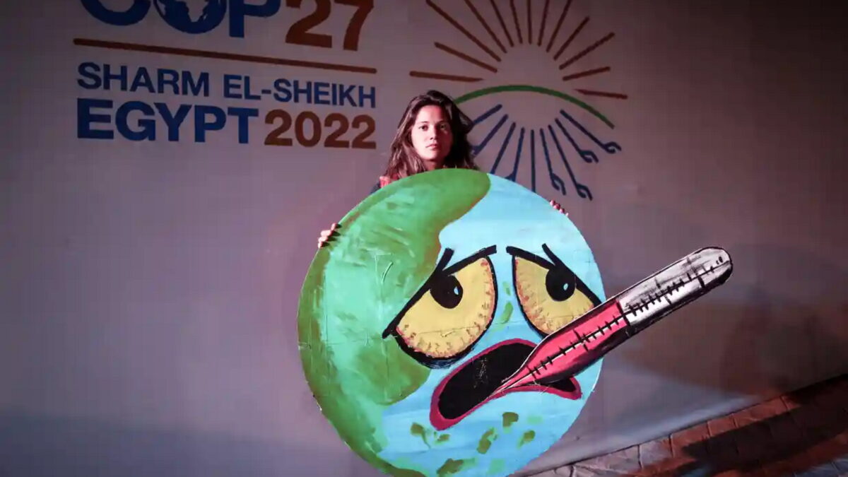 An activist holds a sign showing Earth with a fever and an oral thermometer at the 2022 United Nations Climate Change Conference (COP27), in Sharm El-Sheikh, 19 November 2022. Photo: Sedat Suna / EPA