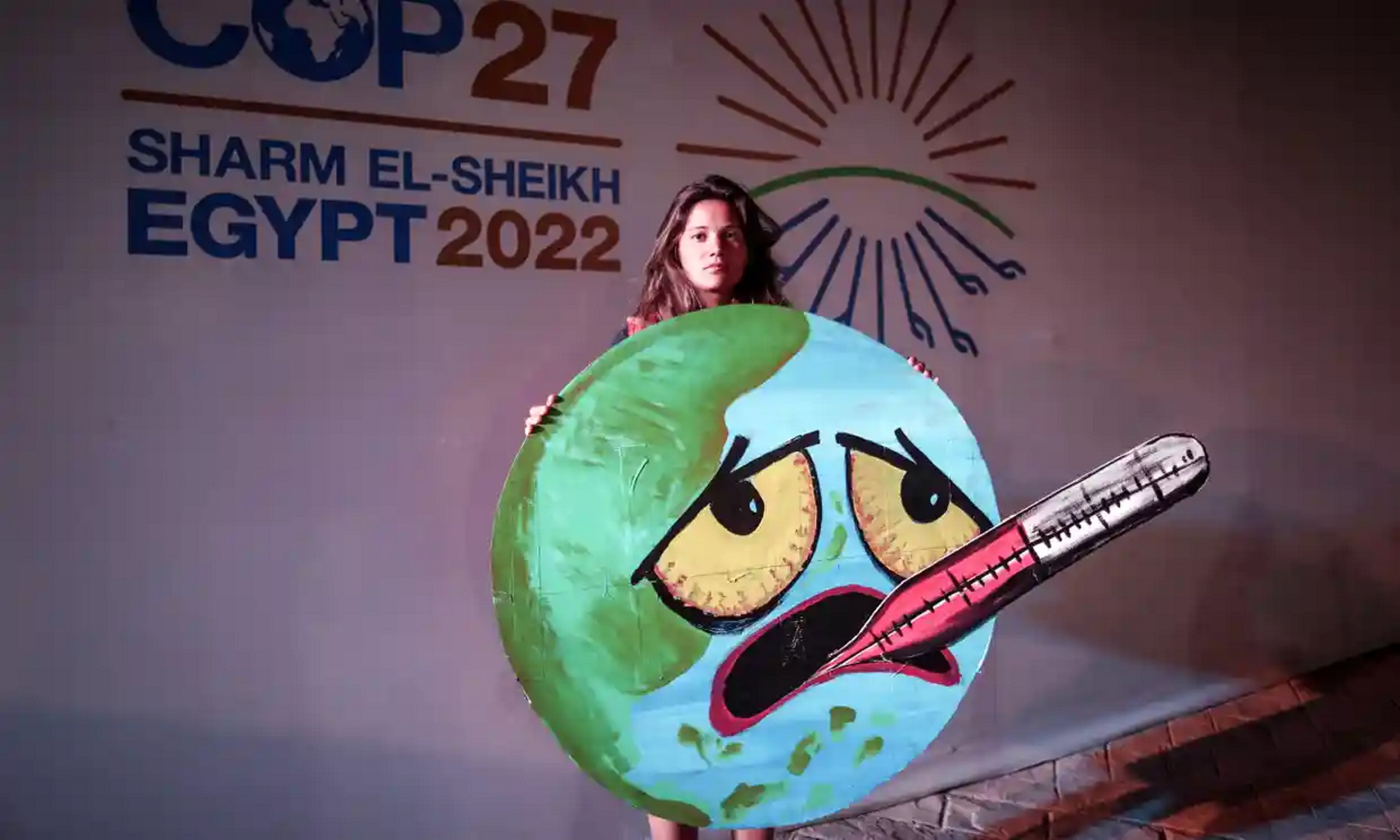 An activist holds a sign showing Earth with a fever and an oral thermometer at the 2022 United Nations Climate Change Conference (COP27), in Sharm El-Sheikh, 19 November 2022. Photo: Sedat Suna / EPA