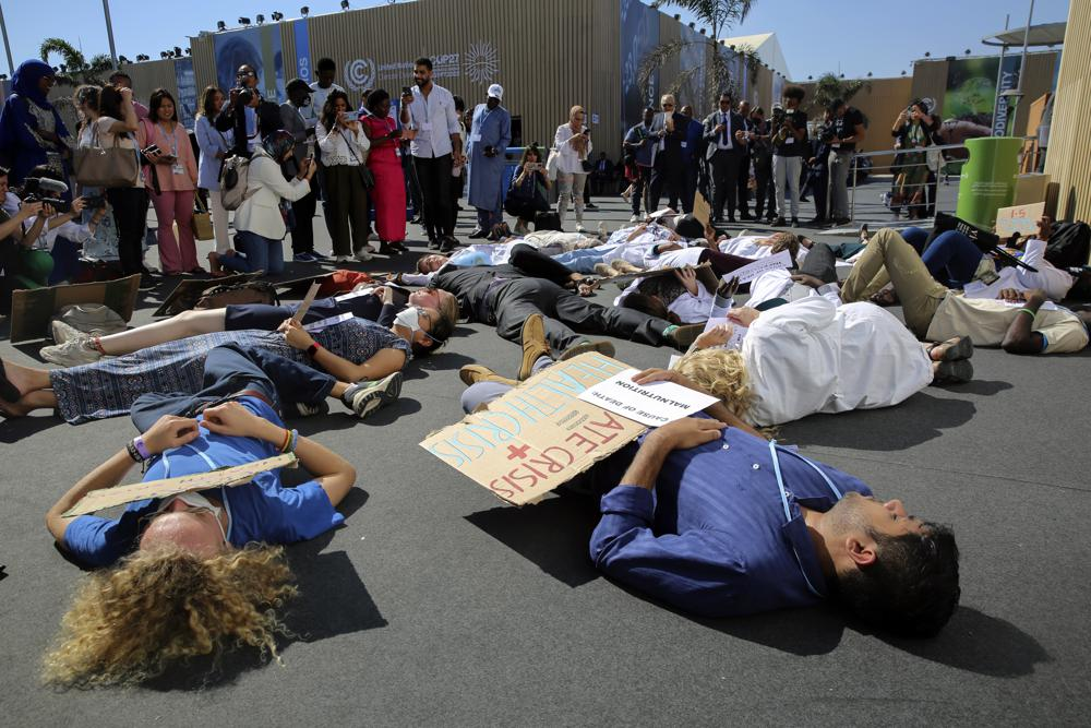 Medical workers from various countries perform a “die-in” to protest the effect of climate change on health issues at the COP27 U.N. Climate Summit, Friday, 11 November 2022, in Sharm el-Sheikh, Egypt. Photo: Thomas Hartwell / AP Photo