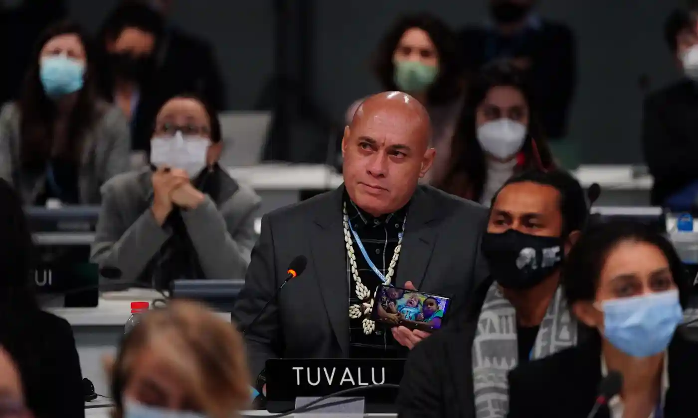 The finance minister from Tuvalu in the South Pacific, Seve Paeniu, holds up an image of his grandchildren during the closing plenary session of the COP27 U.N. Climate Summit on 20 November 2022. Photo: Jane Barlow / PA
