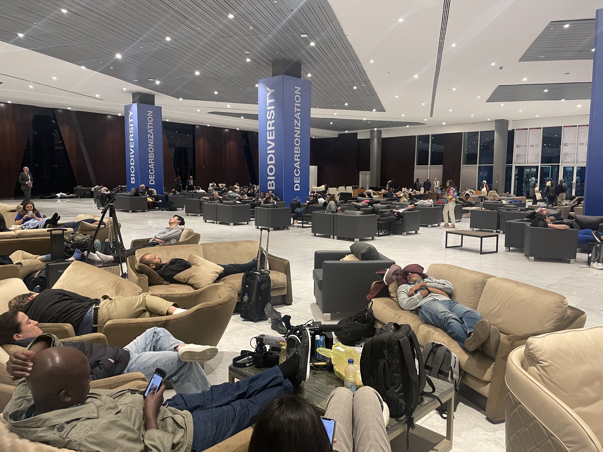 People sleep on couches at 2:26 am in Sharm el-Sheikh, Egypt at the COP27 U.N. Climate Summit on 19 November 2022, while waiting for the cover decision text and plenary. Photo: Simon Lewis / Twitter