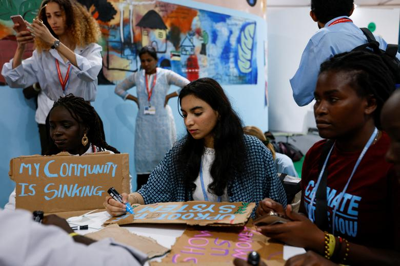 A woman writes on a placard as international climate activists prepare for the “Fridays for Future” strike during the COP27 climate summit, in Sharm el-Sheikh, Egypt, 11 November 2022. Photo: Emilie Madi / REUTERS