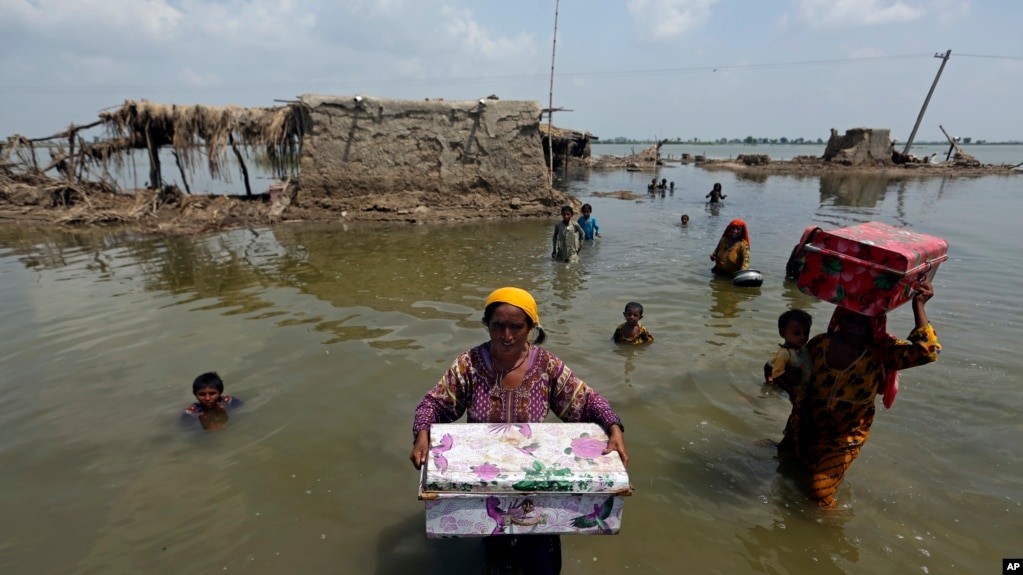 Women carry belongings salvaged from their flooded home after monsoon rains, in the Qambar Shahdadkot district of Sindh Province, of Pakistan, 6 September 2022. Photo: Fareed Khan / AP Photo