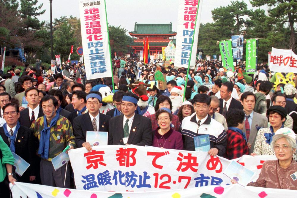 Environmentalists and citizens hold banners calling for reduction of greenhouse gas emissions in front of the Heian shrine in Kyoto, western Japan on 7 December 1997. The world has warmed by more than a degree and spewed a trillion tons of heat-trapping gases since that 1992 summit. Photo: Katsumi Kasahara / AP Photo