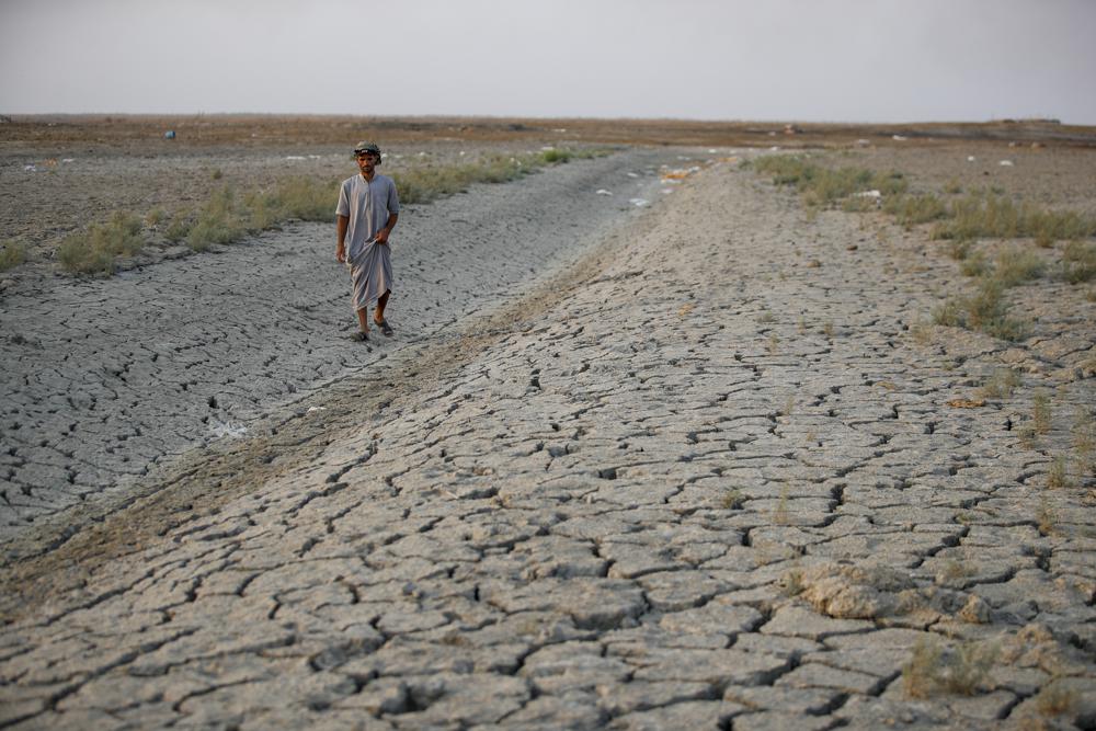 A fisherman walks across a dry patch of land in the marshes of southern Iraq which has suffered dire consequences from back-to-back drought and rising salinity levels, in Dhi Qar province, Iraq, Friday, 2 September 2022. Photo: Anmar Khalil / AP Photo