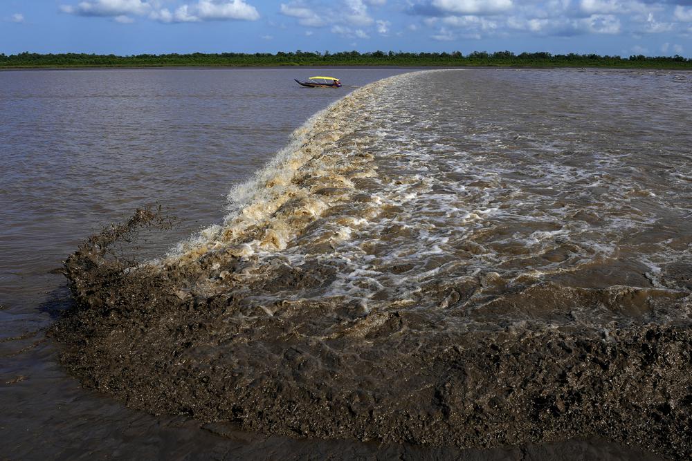 A boat sails in front of a wave caused by the advance of sea water on the river during the dry season in the Bailique Archipelago, district of Macapa, state of Amapa, northern Brazil, Monday, 12 September 2022. During a full moon, the sea invades the river with such strength that, in some places, it turns into a single giant wave of up to 4 meters (13 feet), a phenomenon known as pororoca. Photo: Eraldo Peres / AP Photo