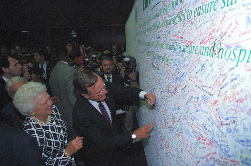 U.S. President George H.W. Bush is watched by first lady Barbara Bush as he signs the Earth Pledge at the Earth Summit in Rio de Janeiro, 12 June 1992. The Earth Pledge says that each signer pledges to work to the best of his or her ability to protect the earth. Photo: M. Frustino / AP Photo