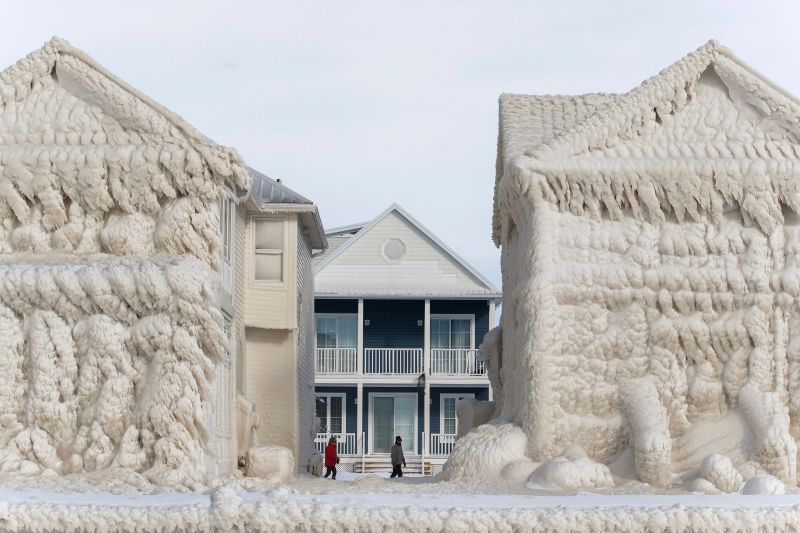 People walk between homes that are covered in ice on Wednesday, 28 December 2022 in the waterfront community of Crystal Beach in Fort Erie, Ontario. Photo: Cole Burston / AFP / Getty Images