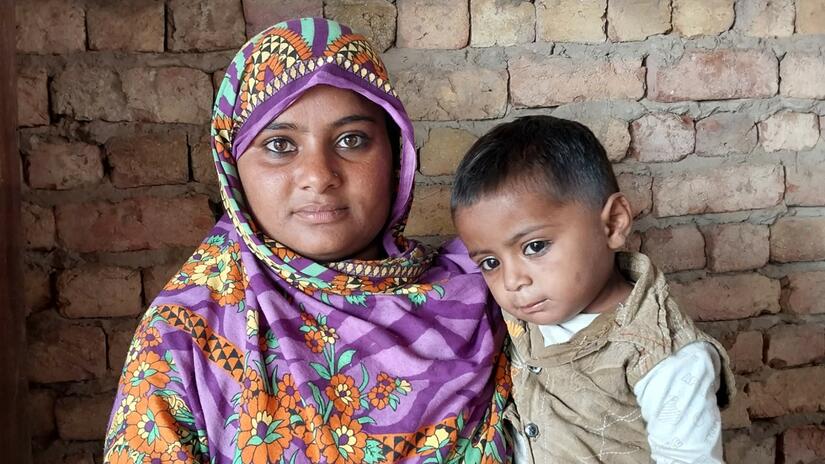Jamila, a mother of four from Sindh province who has been affected by the 2022 floods in Pakistan, holds one of her children. Photo: Angbeen Sohail / IFRC