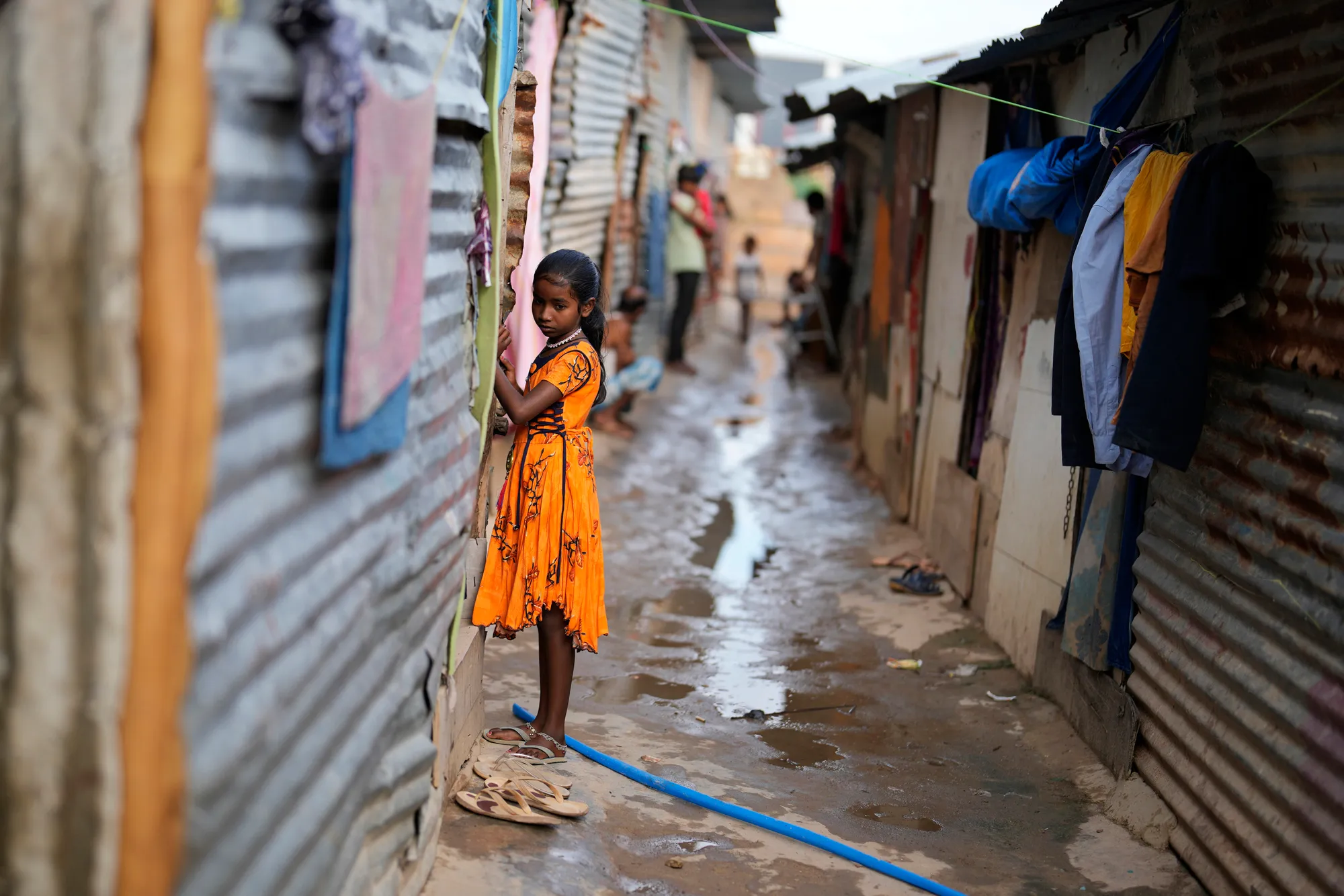 Jerifa Islam stands outside her home on 20 July 2022 in a poor neighborhood in Bengaluru, India, where her family relocated after flooding in 2019 pushed them from their Himalayan village. Photo: Aijaz Rahi / AP Photo