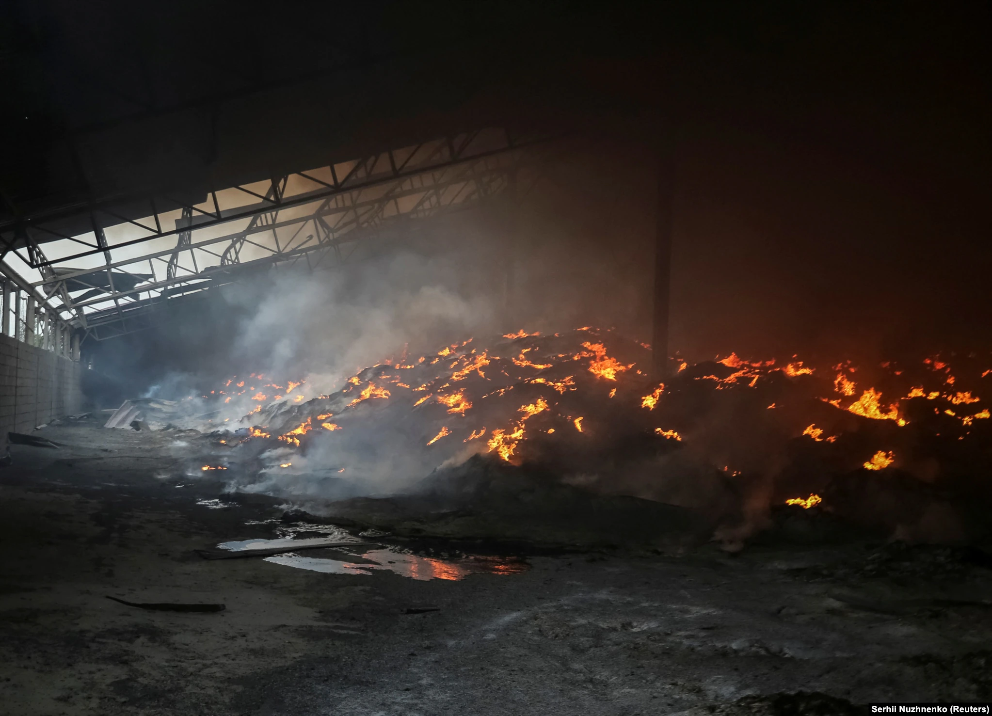 Russian forces have been accused of deliberately targeting food infrastructure in Ukraine. RFE/RL journalists witnessed this storage facility for sunflower seeds burning on 31 May 2022. Ukrainian soldiers claimed the warehouse had been singled out for an artillery strike. Photo: Serhil Nuzhnenko / Reuters