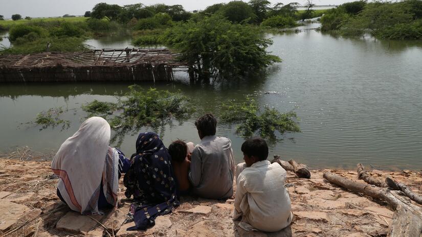 A family in Sujawal district, Sindh province of Pakistan look out at their flooded home which was submerged by the devastating 2022 floods in the country. Photo: Turkish Red Crescent