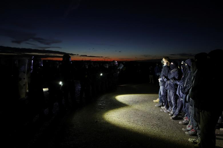 Police officers stand guard as activists protest on 8 January 2023. Protesters oppose the destruction of the hamlet of Luetzerath, Germany for the expansion of the Garzweiler open-cast lignite mine by Germany’s utility RWE. Photo: Thilo Schmuelgen / REUTERS
