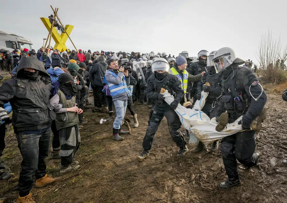 Police officers carry a demonstrator to clear a road at the village Luetzerath near Erkelenz, Germany, Tuesday, 10 January 2023. The village of Luetzerath was occupied by climate activists fighting against the demolishing of the village to expand the Garzweiler lignite coal mine near the Dutch border. Photo: Michael Probst / AP Photo