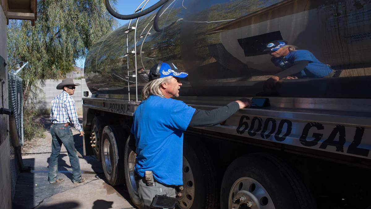 John Hornewer sets alarms on his phone in two-minute intervals, after which he puts a quarter in the fill station, as he fills up his 6,000-gallon tanker to haul water from Apache Junction to Rio Verde Foothills. Photo: Caitlin O'Hara / The Washington Post