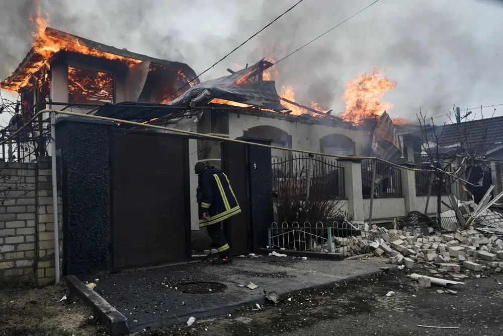 A firefighter stands at a burning house hit by the Russian shelling in Kherson, Ukraine, on the Orthodox Christmas Eve Friday, 6 January 2023. Photo: LIBKOS / AP Photo