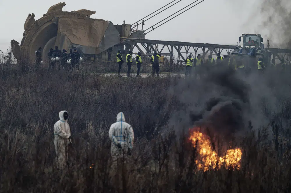 A lignite excavator works as activists build barricades and set them on fire while the police make preparations for the planned eviction of the village of Luetzerath, western Germany, Monday, 2 January 2023. The village of Luetzerath was to be demolished to expand the Garzweiler lignite coal mine near the Dutch border. Photo: Henning Kaiser / dpa / AP