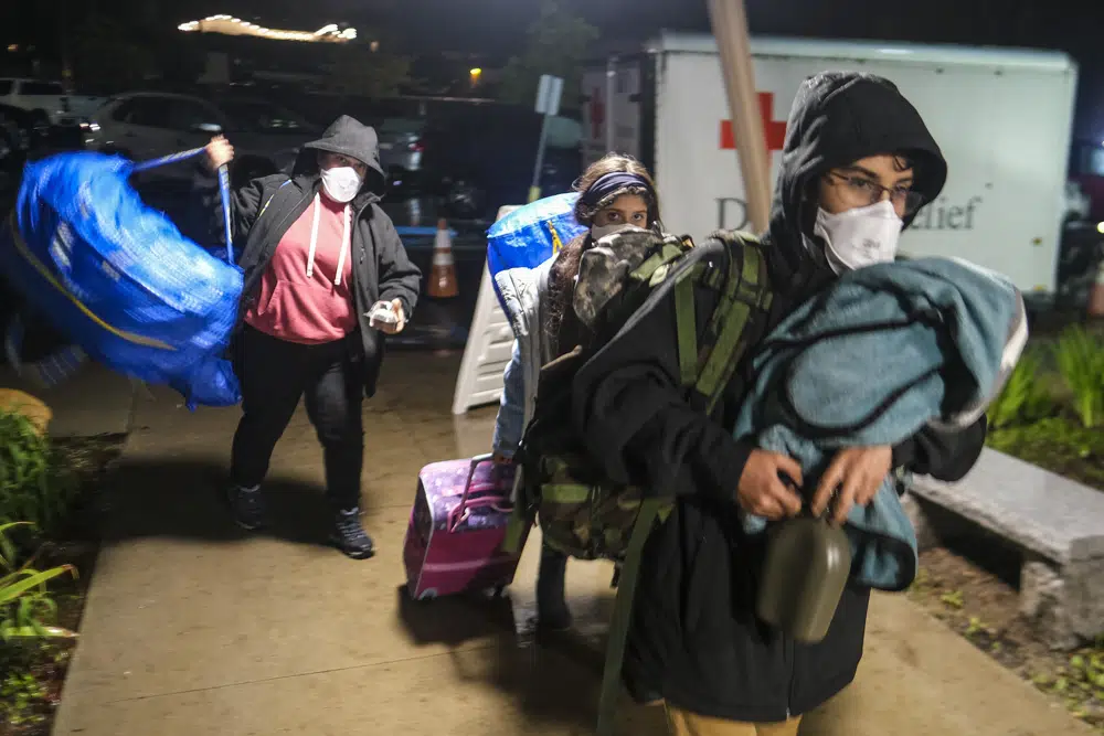 People carrying their belongings arrive at an evacuation center in Santa Barbara, California, Monday, 9 January 2023, during record flooding. Photo: Ringo H.W. Chiu / AP Photo
