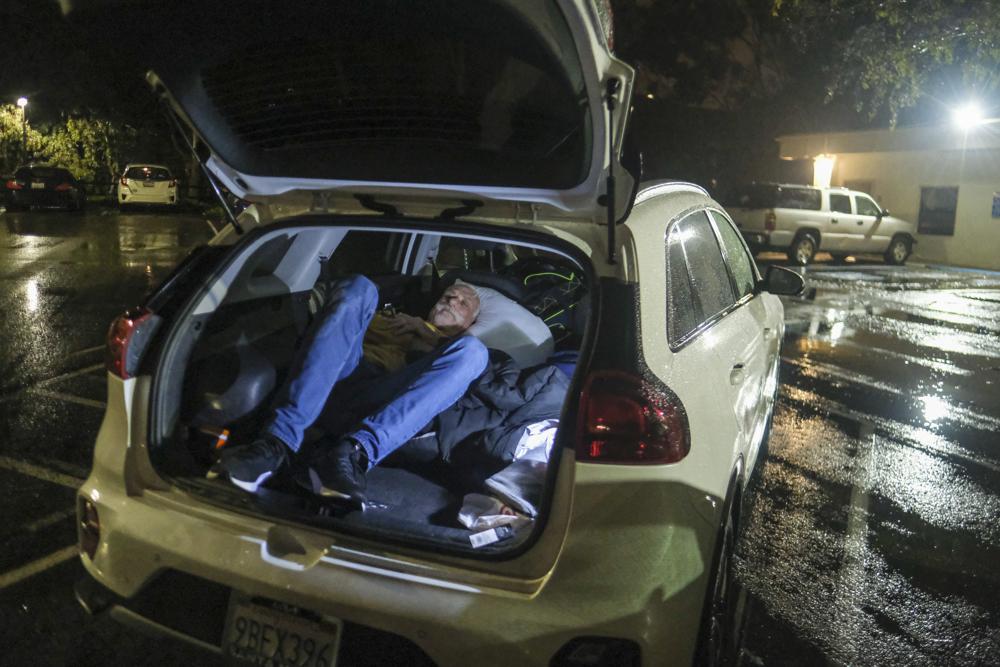 Duck Derrington, 61 of Lompoc, sleeps in his car at the parking lot of an evacuation center in Santa Barbara, California, Monday, 9 January 2023, during record flooding. Photo: Ringo H.W. Chiu / AP Photo