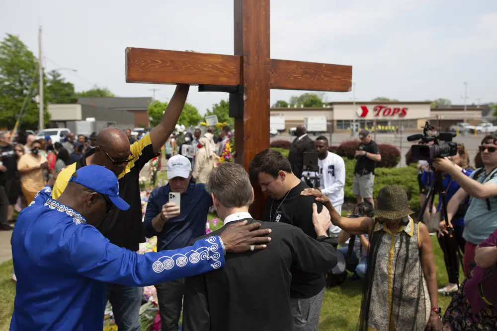 A group prays at the site of a memorial for the victims of the Buffalo supermarket shooting outside the Tops Friendly Market on 21 May 2022, in Buffalo, N.Y. The number of U.S. mass killings linked to extremism was at least three times higher in the last decade than the total from any 10-year period since the 1970s. That’s according to a report released to The Associated Press by the Anti-Defamation League. Photo: Joshua Bessex / AP Photo
