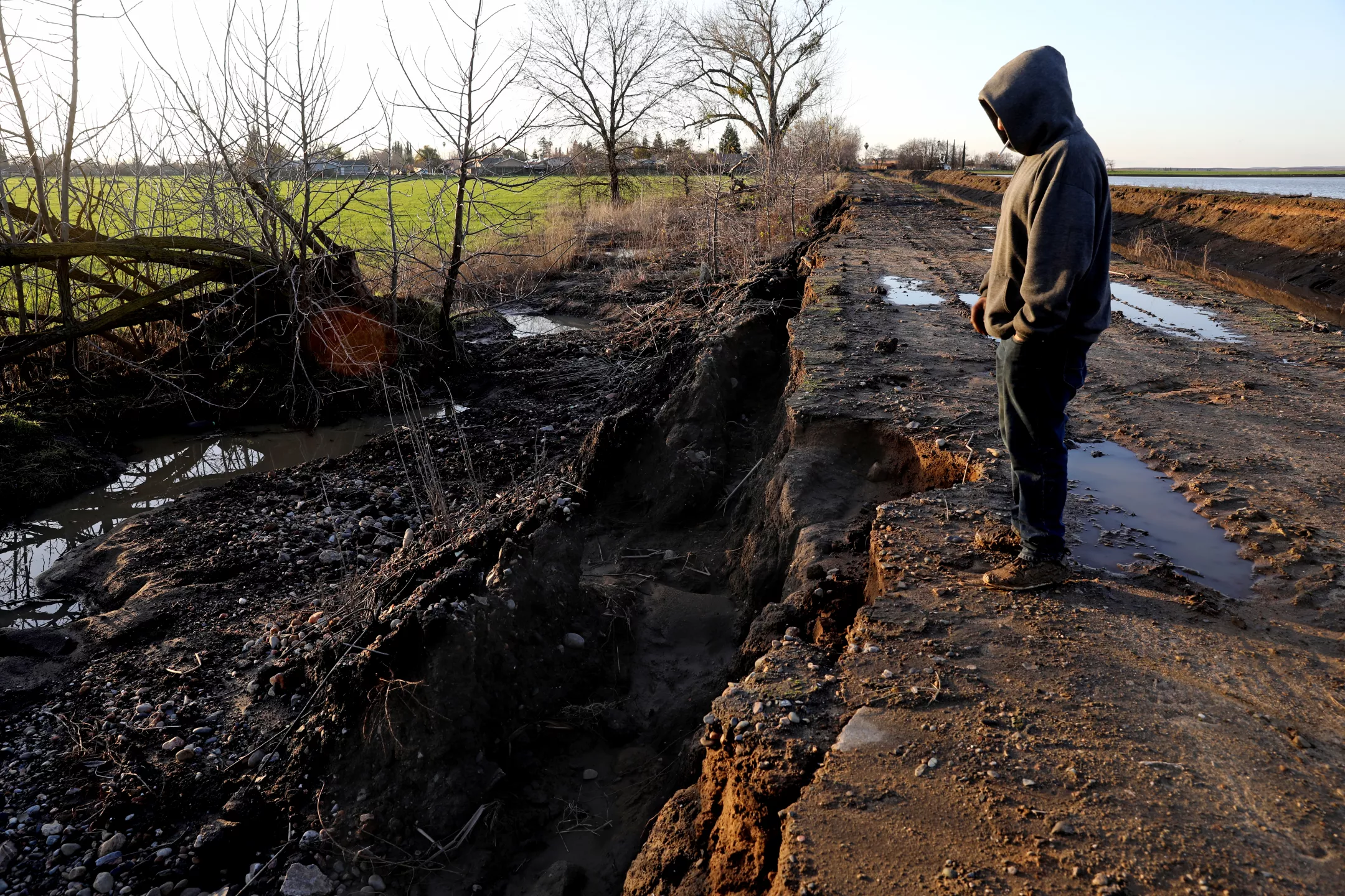 Adam Gonzales stands where the California storms in January 2023 caused the Planada Canal and Miles Creek to overflow and flood the town of Planada. Photo: Gary Coronado / Los Angeles Times