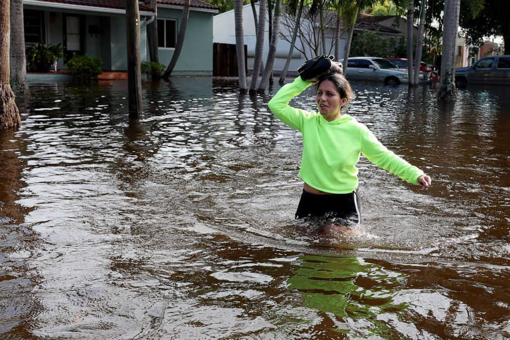 Katherine Arroyo walks through a flooded street after record rains fell in the area, 13 April 2023, in Hollywood, Florida. Photo: Joe Raedle / Getty Images