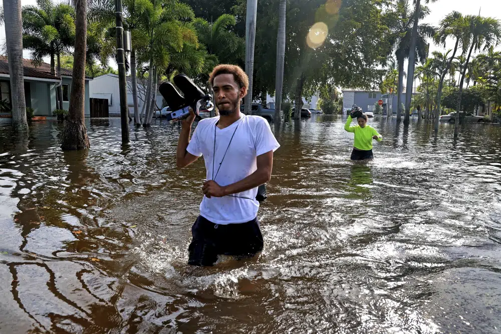 James Richard and Katherine Arroyo trudge through the water in Hollywood, Florida, on 13 April 2023. MOre than 25 inches of rain fell in South Florida since Monday, causing widespread flooding. Photo: Mike Stocker / South Florida Sun-Sentinel / AP