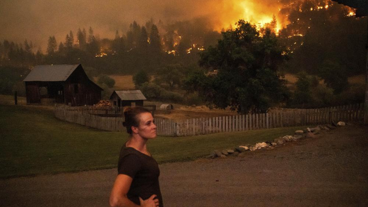 Angela Crawford watches as a wildfire called the McKinney fire burns a hillside above her home in Klamath National Forest, California, on Saturday, 30 July 2022. Crawford and her husband stayed, as other residents evacuated, to defend their home from the fire. Photo: Noah Berger / AP Photo