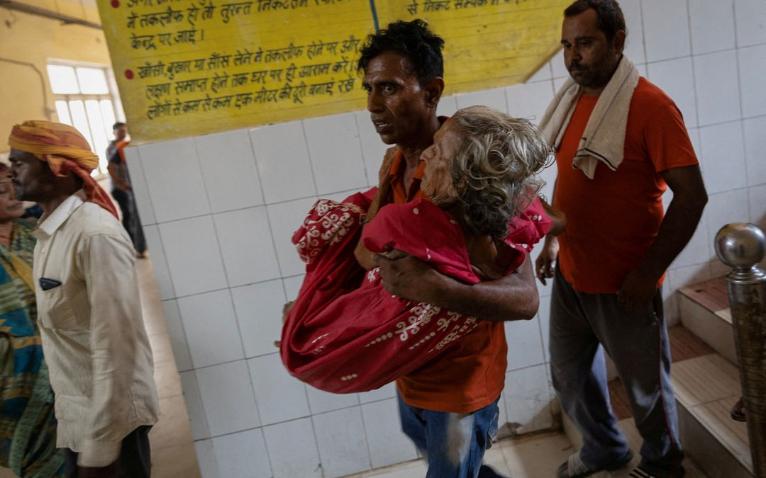 A man carries his mother as he arrives at an emergency ward at a hospital in Ballia District in the northern state of Uttar Pradesh, India, 21 June 2023. Photo: Adnan Abidi / REUTERS