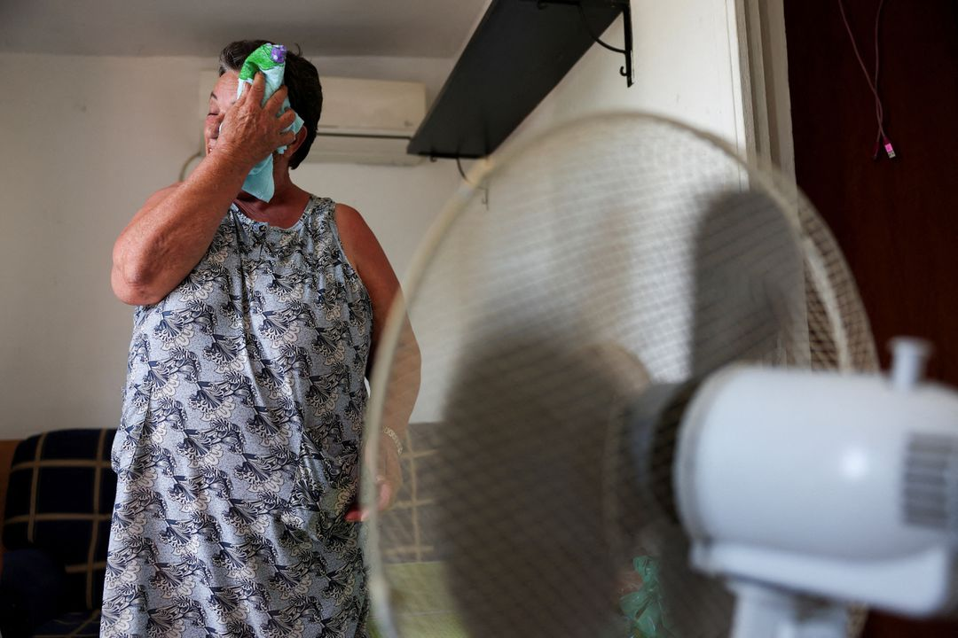 Monica Garcia, 65, wipes her sweat with a cloth while standing in front of a fan, as residents of Canada Real neighbourhood struggle with scorching temperatures amid first heatwave of the summer, in Madrid, Spain, 26 June 2023. The mother-of-three, who has lived at the shanty town for over 20 years, is waiting to be rehoused after a fire burnt her previous home. Photo: Isabel Infantes / REUTERS