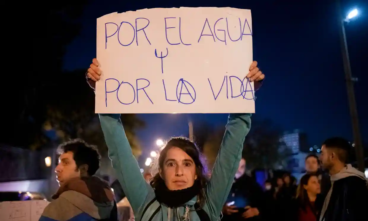 A protester holds a sign that reads “For water, for life” in Montevideo in May 2023. Photo: Santiago Mazzarovich / AP