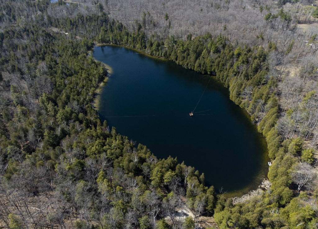 An aerial view of Crawford Lake as a team consisting of scientists from Carleton University and Brock University gather sediment layer samples from the lake bottom at the Crawford Lake Conservation Area near Milton, Ontario, Canada, 12 April 2023. The view under the surface of Crawford Lake tells a different story. Scientists believe the lake's exceptionally well-preserved sediment layers serve as a reference point for a proposed new geological chapter in the planet's history, defined by the considerable changes wrought by human activity: the Anthropocene. The International Commission on Stratigraphy's Anthropocene Working Group on 11 July 2023, named the lake as the embodiment of the proposed Anthropocene epoch. Photo: Peter POWER / AFP