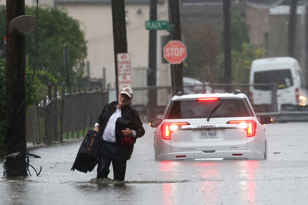 A man carries his belongings as he abandons his vehicle which stalled in floodwaters during a heavy rain storm in the New York City suburb of Mamaroneck in Westchester County, New York, U.S., 29 September 2023. Photo: Mike Segar / REUTERS