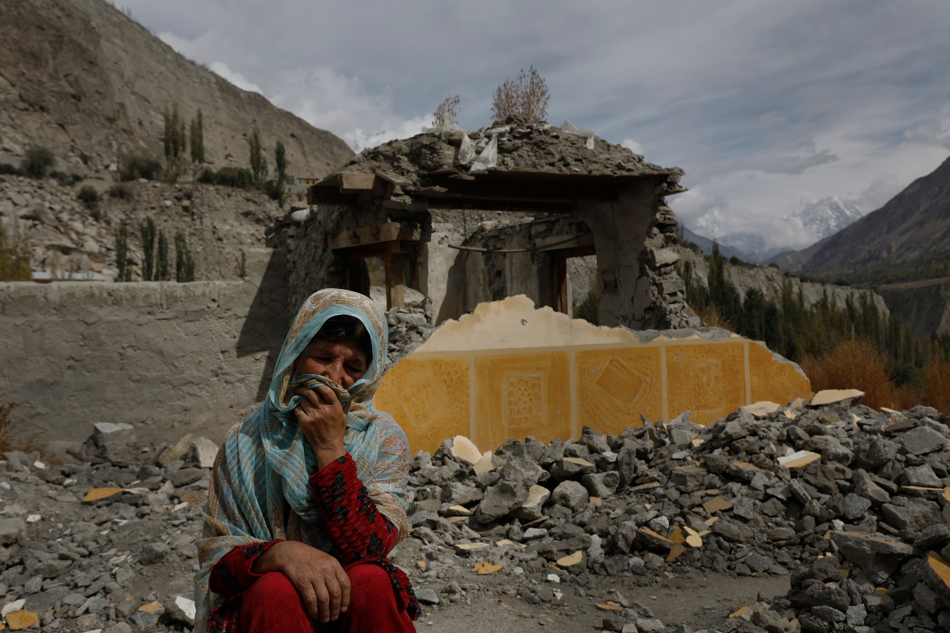 Dilshad Bano, 51, sits on the floor near her house which was damaged after a Glacial Lake Outburst Flooding (GLOF) incident, in Hassanabad village, Pakistan, 9 October 2023 Photo: Akhtar Soomro / REUTERS