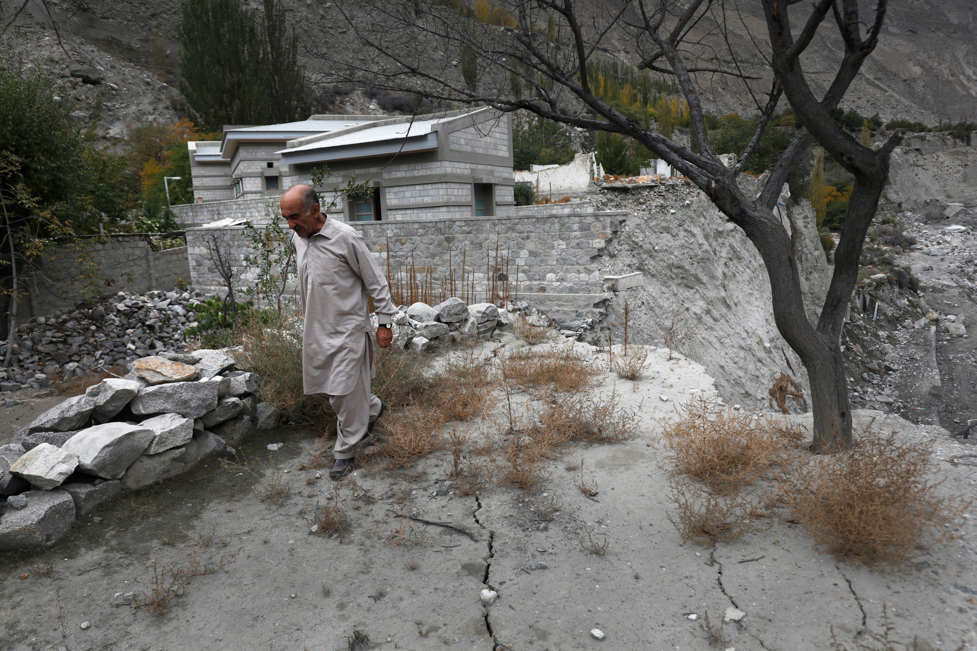 Community leader Sultan Ali, 70, walks over cracks that developed after a Glacial Lake Outburst Flooding (GLOF) swept away part of the land in Hassanabad village, Pakistan, 9 October 2023. Photo: Akhtar Soomro / REUTERS