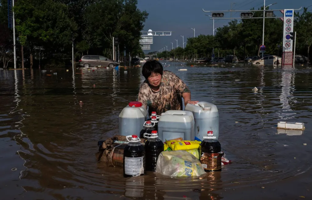 A woman pushes a makeshift raft full of goods salvaged from a building as she wades through receding floodwaters on 5 August 2023 in Zhuozhou, Hebei Province south of Beijing, China. The extreme rainfall from Typhoon Doksuri was the heaviest to hit Beijing in 140 years of record-keeping, inundating the capital and triggering flash floods and landslides. More than 100,000 people were evacuated from the hard-hit city of Zhuozhou, where rescuers used rafts to reach people trapped in villages cut off by deep water. Photo: Kevin Frayer / Getty Images