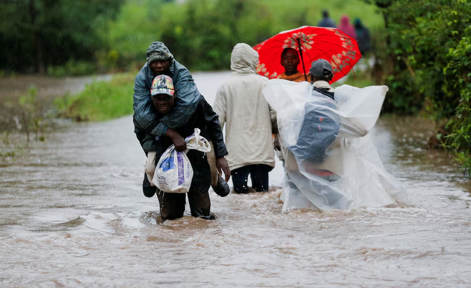 Residents wade through flood waters after a seasonal river burst its banks following heavy rainfall in Kitengela municipality of Kajiado County, near Nairobi, Kenya, 1 May 2024. Photo: Thomas Mukoya / REUTERS