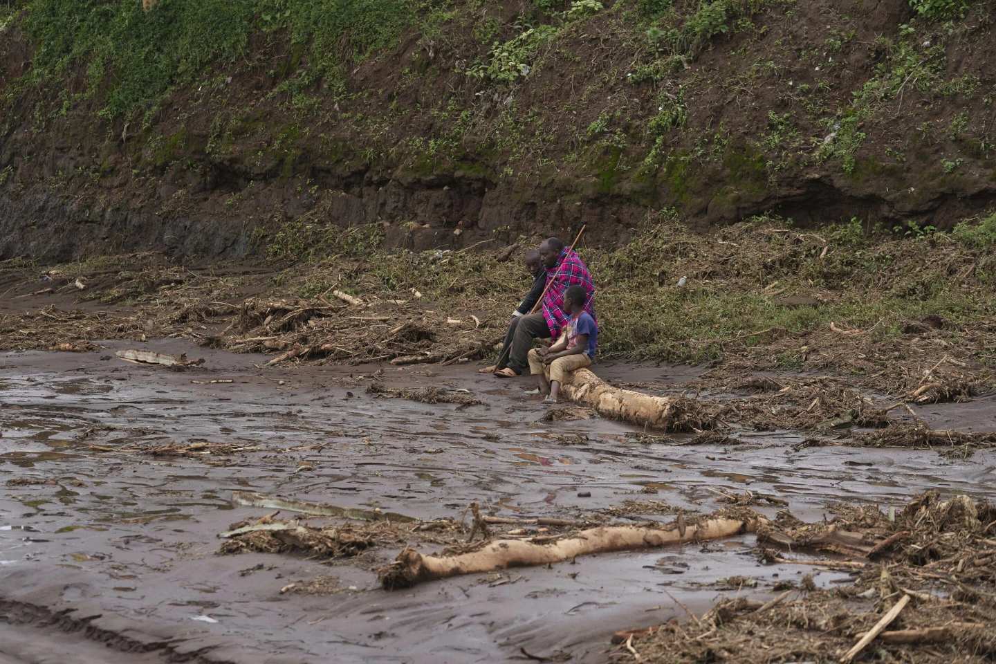 A man sits with children on a log, after floodwater washed away houses, in Kamuchiri Village Mai Mahiu, Nakuru County, Kenya, 30 April 2024. The impact of the calamitous rains that struck East Africa from March to May was intensified by a mix of climate change and rapid growth of urban areas, an international team of climate scientists said in a study. Photo: Brian Inganga / AP Photo