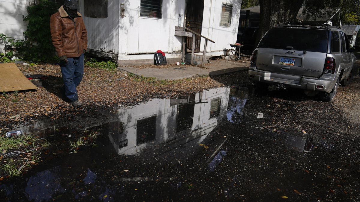 A man stands near his home looking at a street he says has been flooded for months, on Thursday, 7 December 2023, in Prichard, Alabama. Water bubbles up in streets, pooling in neighborhoods for weeks or months. Homes burn to the ground if firefighters can’t draw enough water from hydrants. Utility crews struggle to fix broken pipes while water flows through shut-off valves that don’t work. Photo: Brynn Anderson / AP Photo