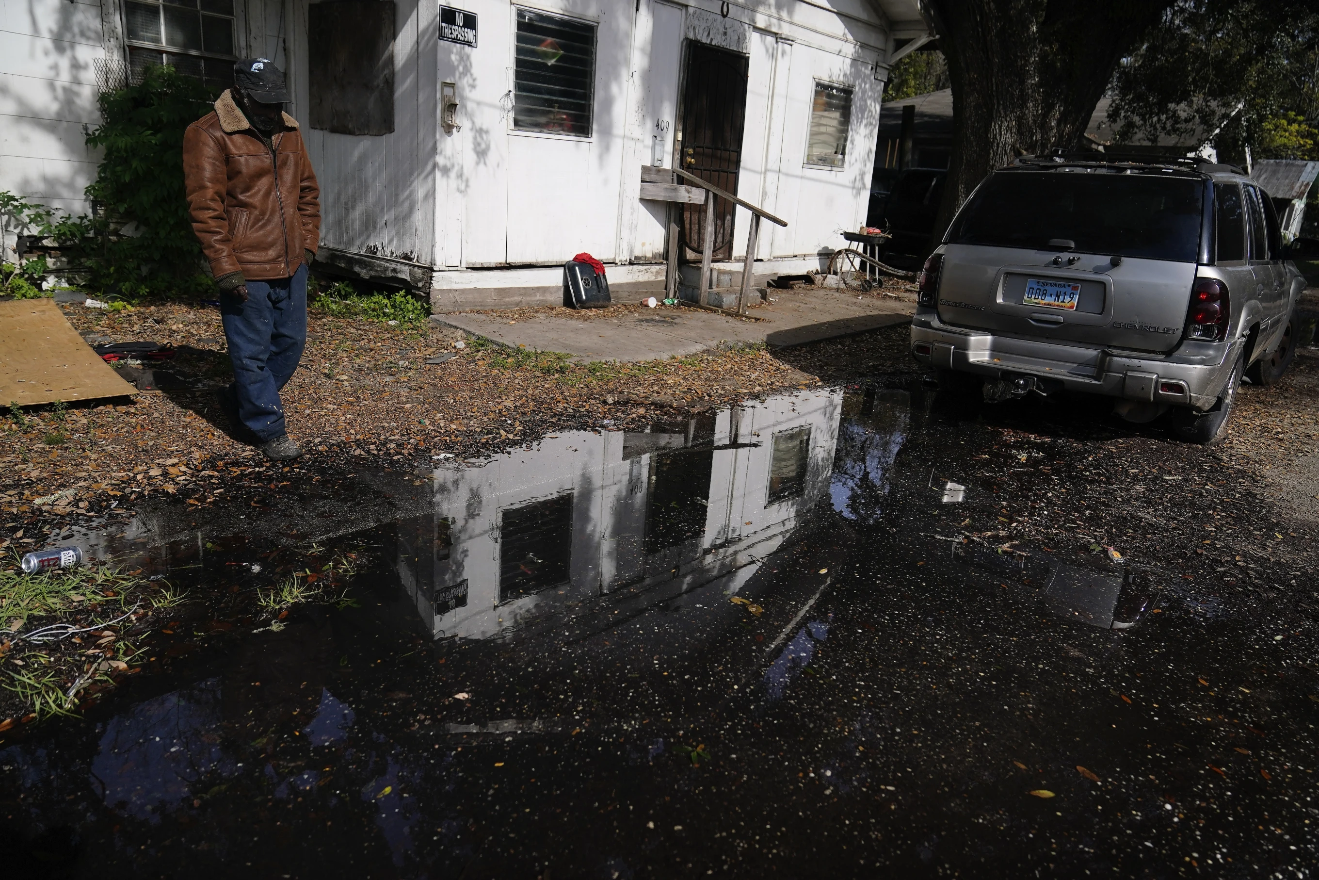 A man stands near his home looking at a street he says has been flooded for months, on Thursday, 7 December 2023, in Prichard, Alabama. Water bubbles up in streets, pooling in neighborhoods for weeks or months. Homes burn to the ground if firefighters can’t draw enough water from hydrants. Utility crews struggle to fix broken pipes while water flows through shut-off valves that don’t work. Photo: Brynn Anderson / AP Photo