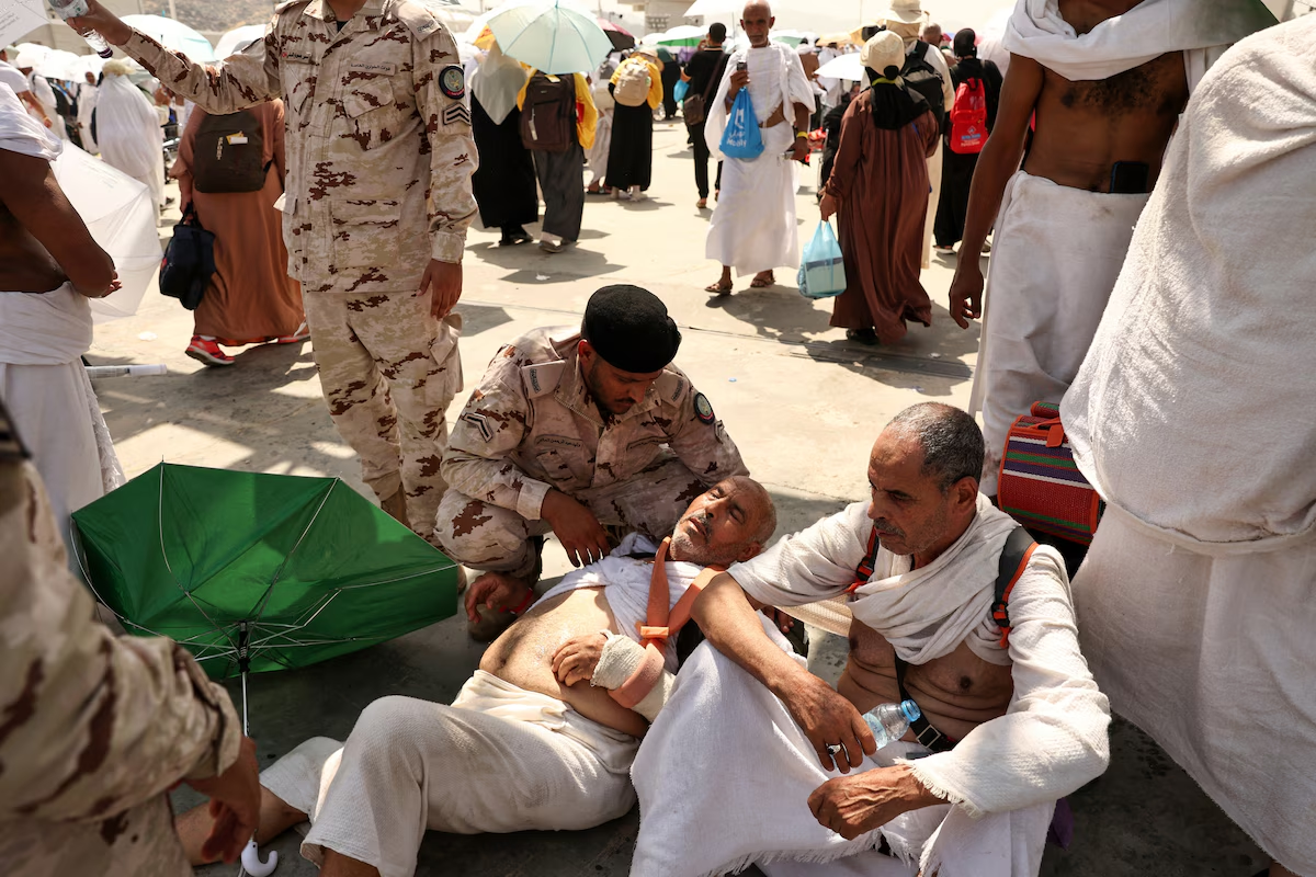 A man affected by the scorching heat on Sunday, 16 June 2024 is helped by a member of the Saudi security forces during the Hajj pilgrimage to Saudi Arabia’s holy city of Mecca. Photo: Fadel Senna / AFP / Getty Images