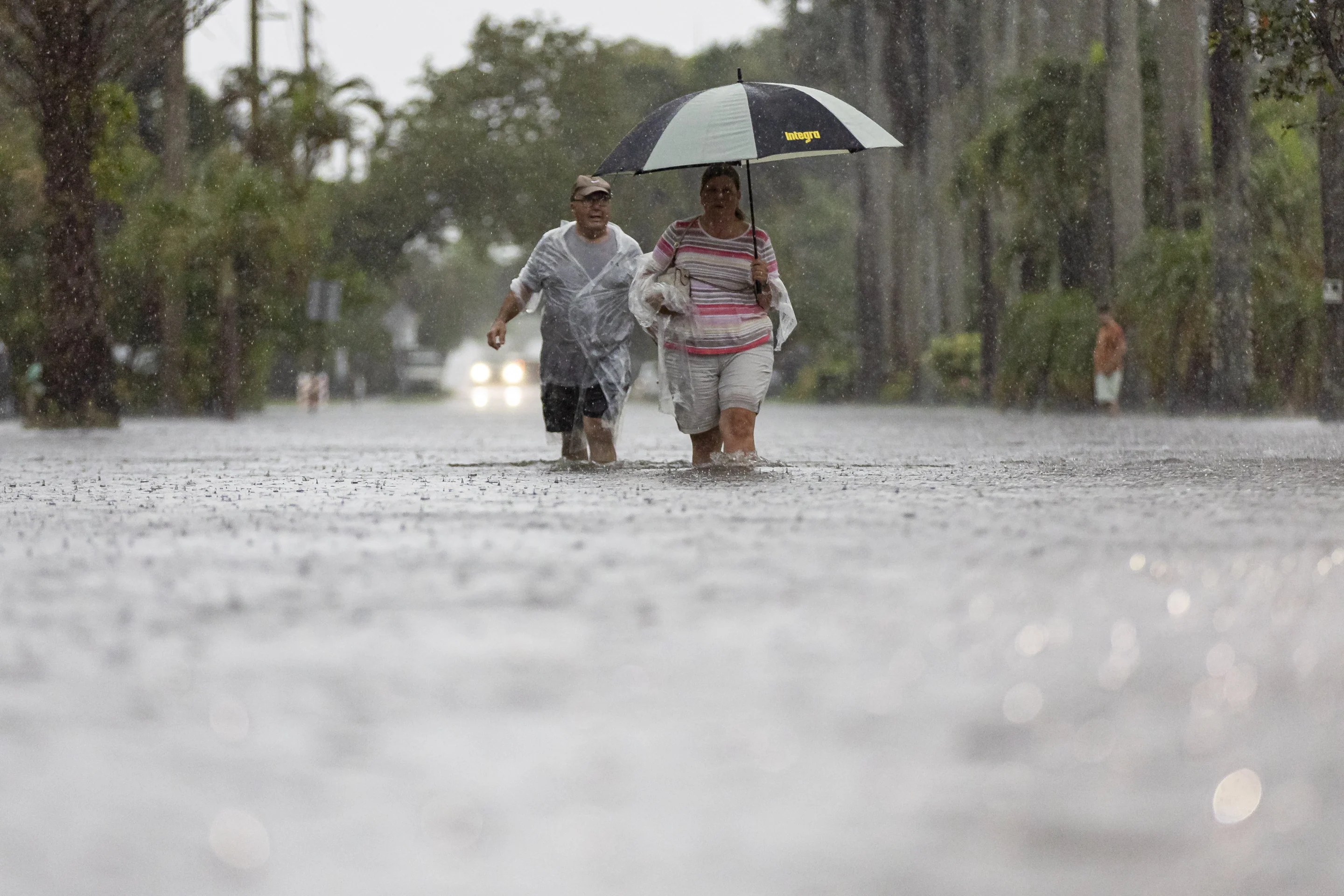 Jim Comunale and Pam Mervos walk down Arthur Street as heavy rain floods the surrounding neighborhood on Wednesday, 12 June 2024, in Hollywood, Florida. Photo: Matias J. Ocner / Miami Herald / AP