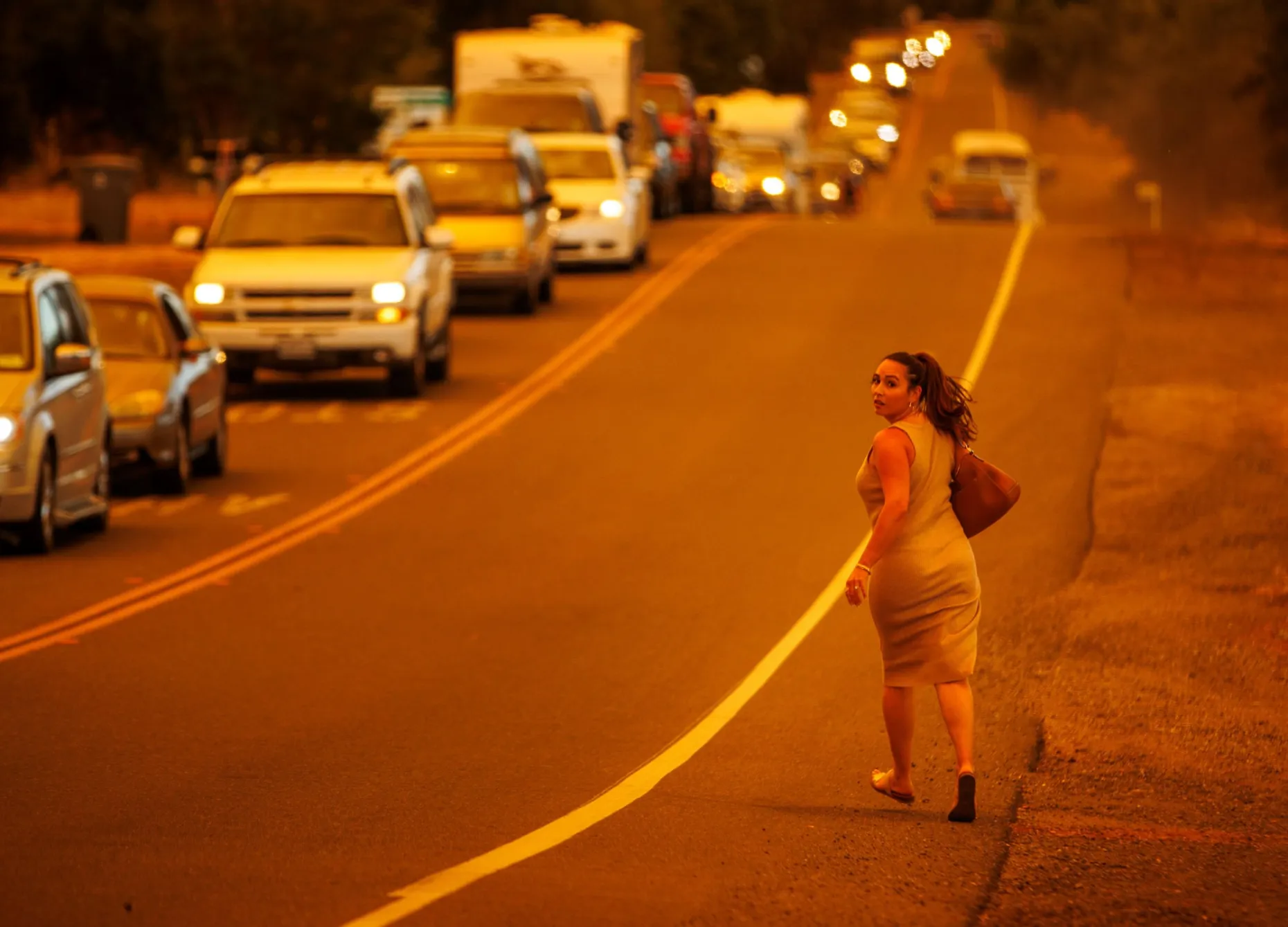 A women runs while cars evacuate as the Thompson Fire burns, Tuesday, 2 July 2024, in Oroville, California. Photo: Ethan Swope / AP