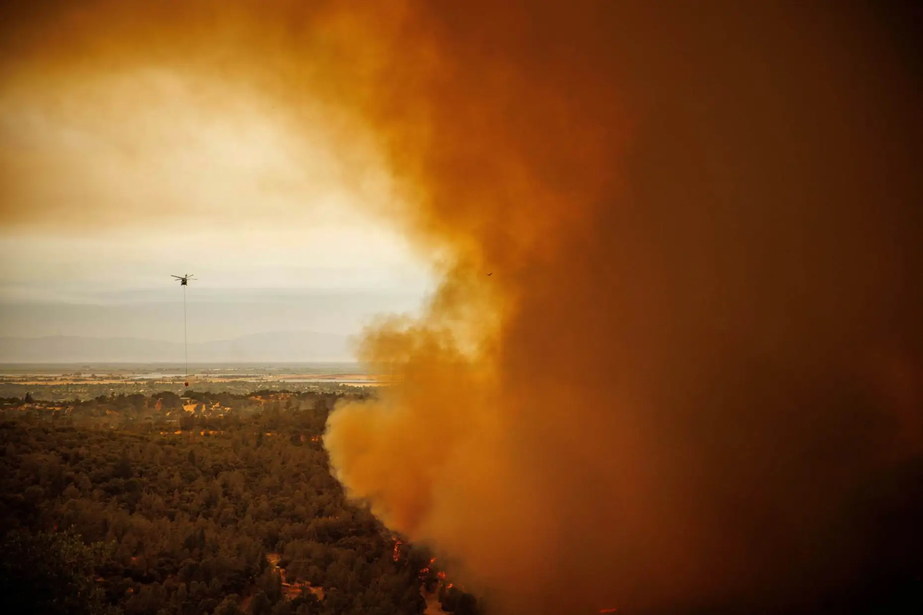 A helicopter drops water as the Thompson Fire burns, Tuesday, 2 July 2024, in Oroville, California. Photo: Ethan Swope / AP