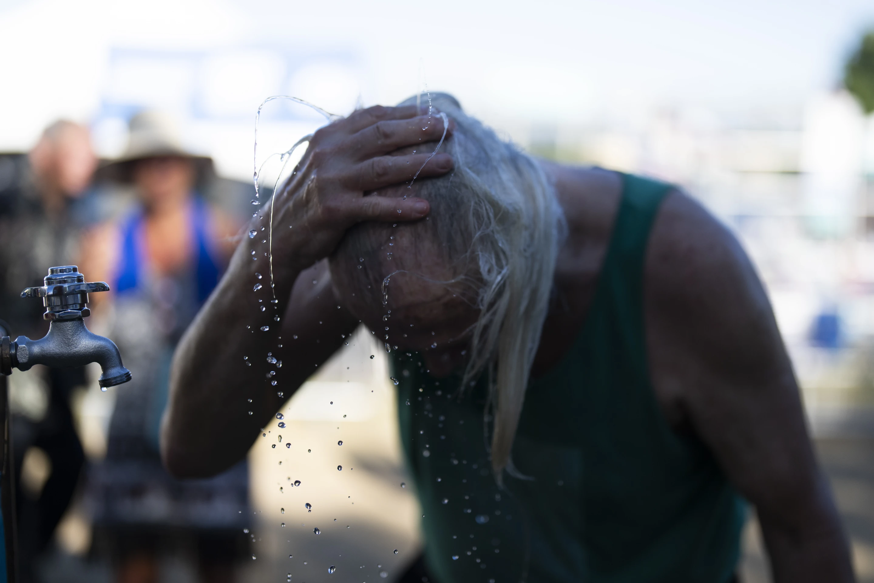 A person cools off during the Waterfront Blues Festival on Friday, 5 July 2024, in Portland, Ore. A slow-moving and record-setting heat wave spread across the Western U.S., sending many residents in search of a cool haven from the dangerously high temperatures. Photo: Jenny Kane / AP Photo