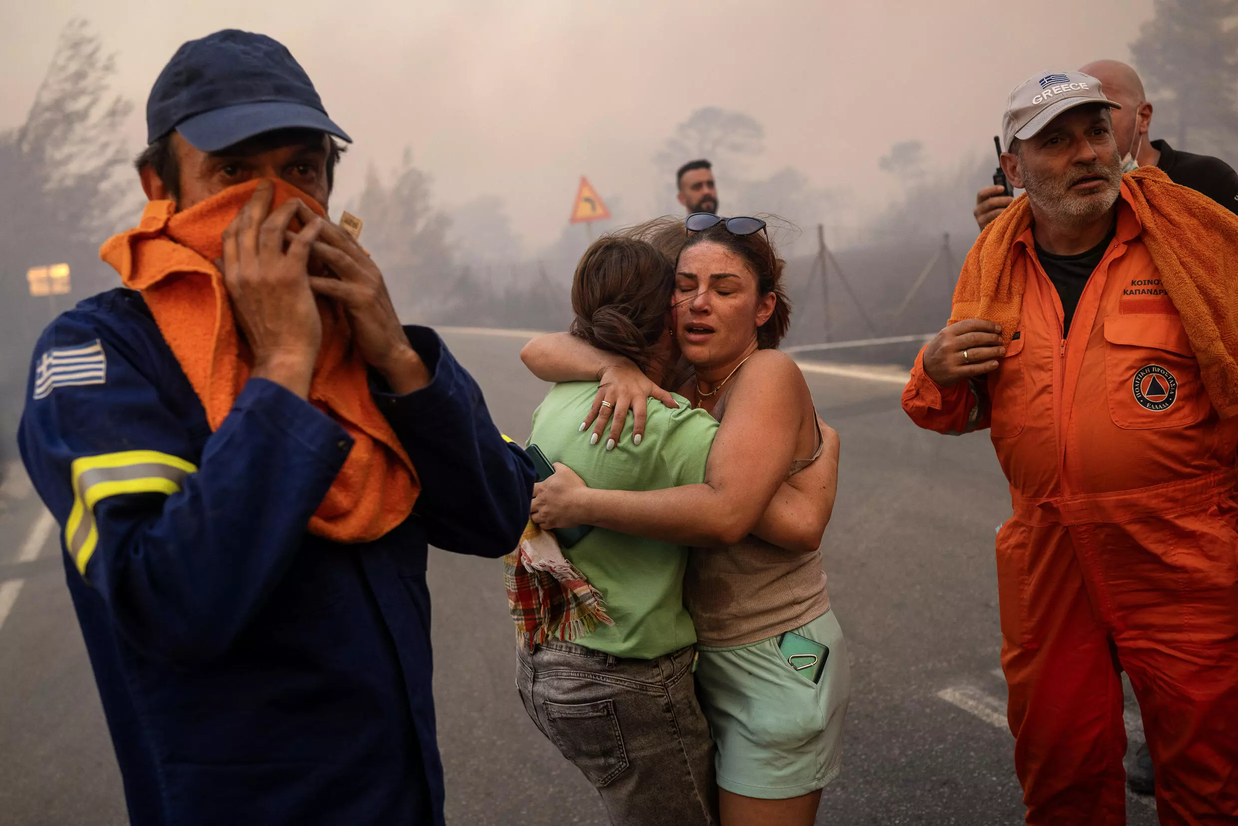 Two women embrace after being rescued during a wildfire in Varnavas, north of Athens, 12 August 2024. Photo: Angelos TZORTZINIS / AFP