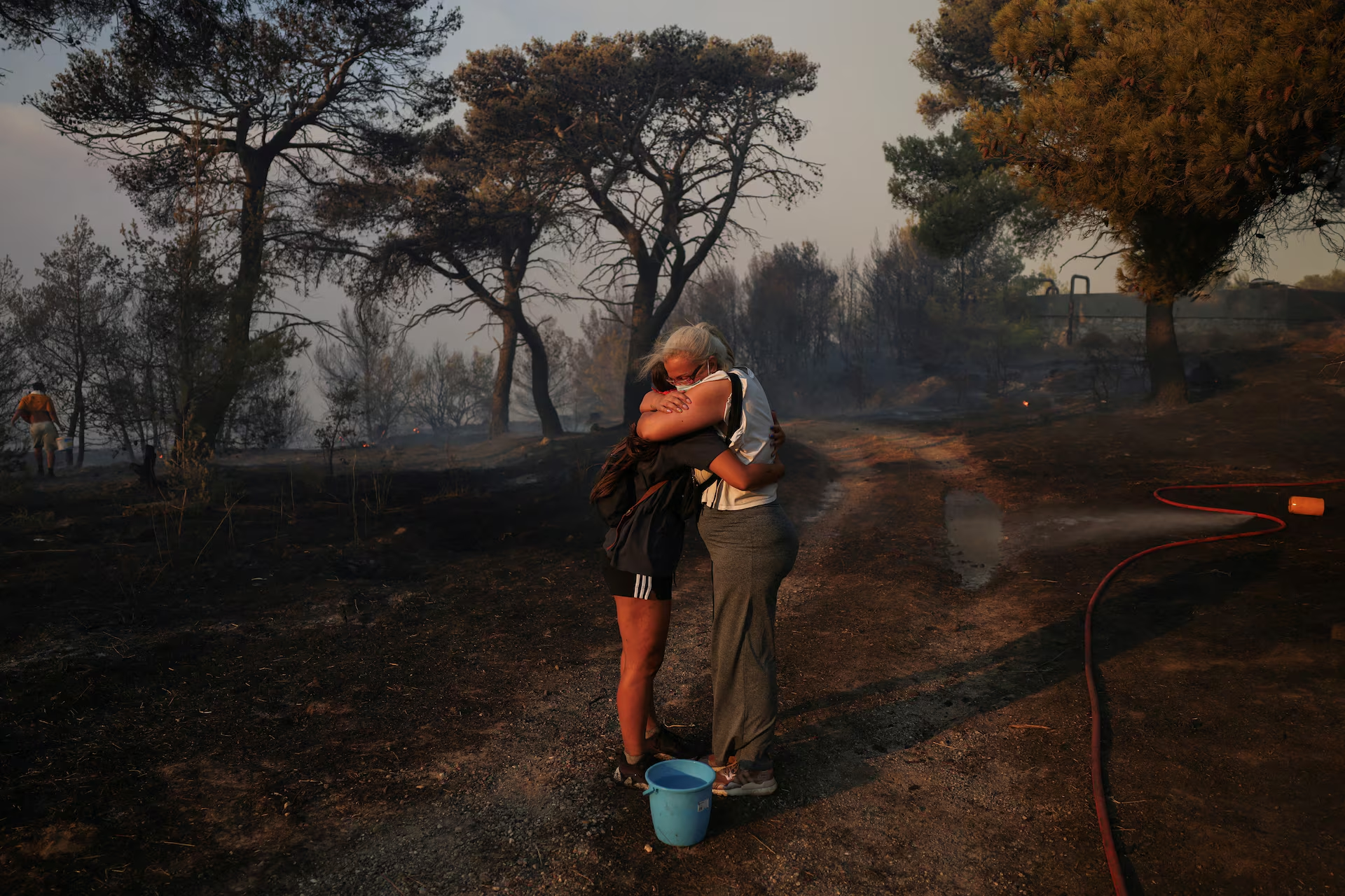 Marina Kalogerakou, 24, hugs her aunt Eleonora Zoakou, 48, as a wildfire burns in Penteli, Greece, 12 August 2024. Photo: Stelios Misinas / REUTERS