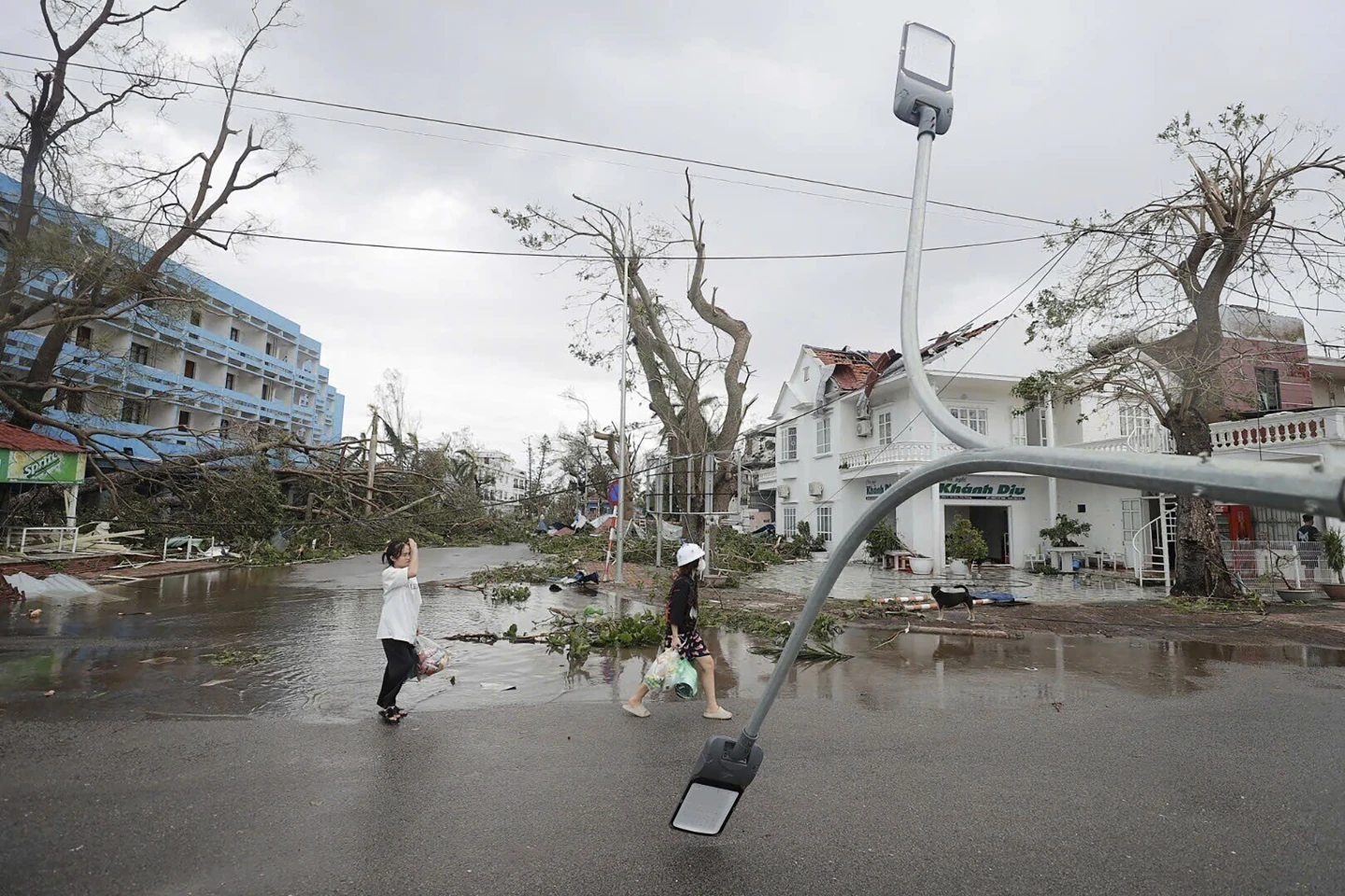 People walk past broken light post after typhoon Yagi hit the city, in Hai Phong, northern Vietnam on Sunday, 8 September 2024. Photo: Minh Quyet / VNA / AP